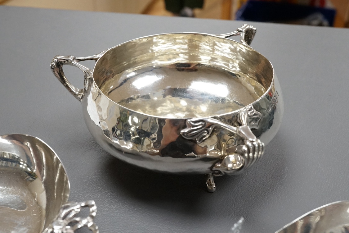 An Edwardian Art Nouveau planished silver tri-handled bowl by Charles Edwards, London, 1905, with stylised handles, diameter 94mm excluding handles, together with a pair of later silver two handled bonbon dishes, Deakin